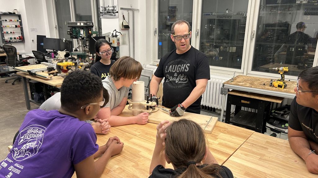 AB Mentor Adam Salem helps the RoHawk team members build a prototype of a claw to grab the game piece.