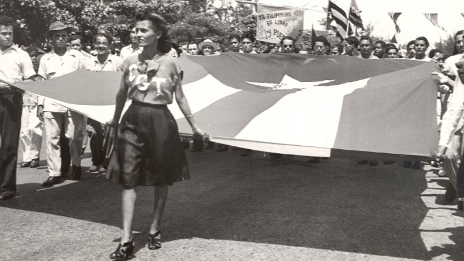 Parade carrying of Puerto Rican flag, Sign in the back reads “Ya Filipinas es libre. Y Puerto Rico?” (“The Philippines are already free. And Puerto Rico?”) Offices of the Government of Puerto Rico in the United States (OGPRUS) Records