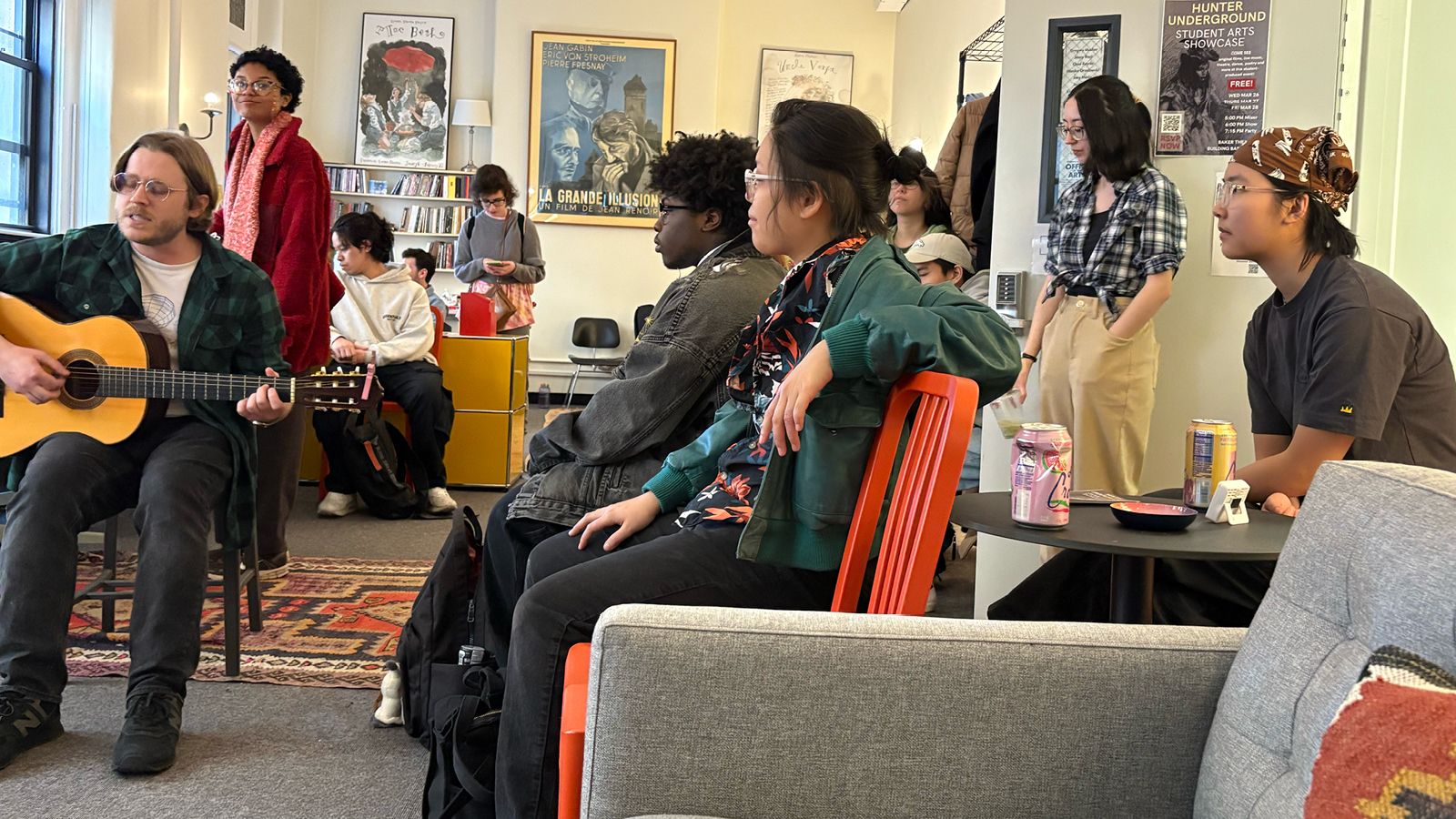 Students listening to another student play guitar and sing at an Arts Meet-Up