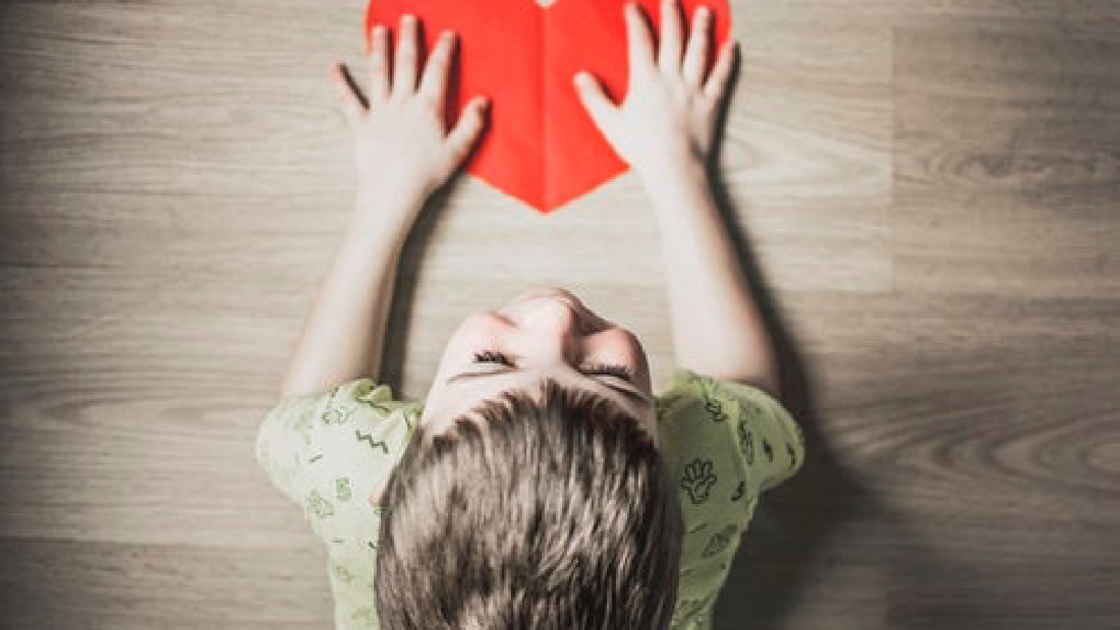 boy holding paper heart on table