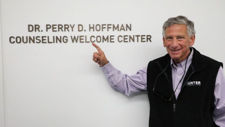 Philanthropist Bruce Hoffman points at the sign of the Welcome Center, named in honor of his late wife.