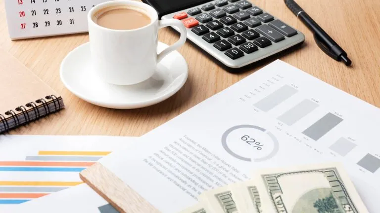 Money, a cup of tea, and calculator on a desk