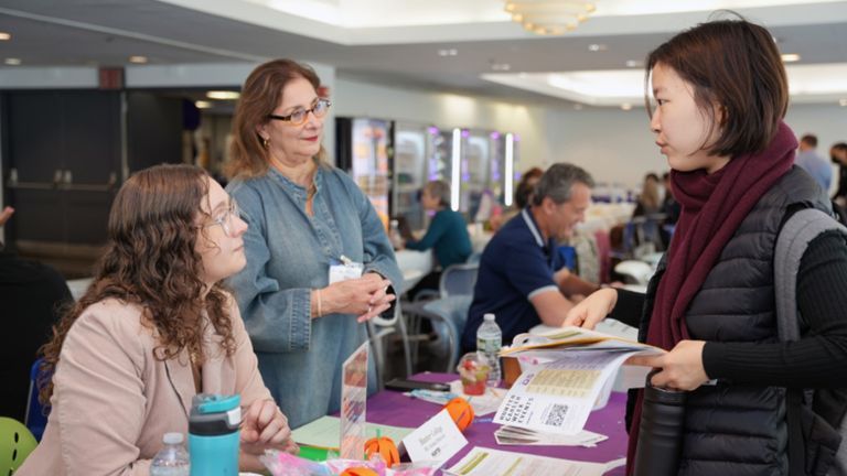 A group of people talking at a tabling.
