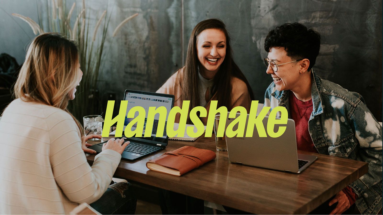 students chatting and smiling around table while working