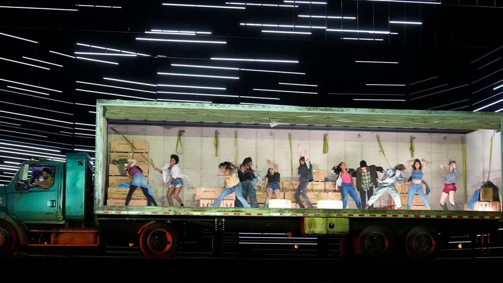 Performers dancing in the back of a truck on stage.