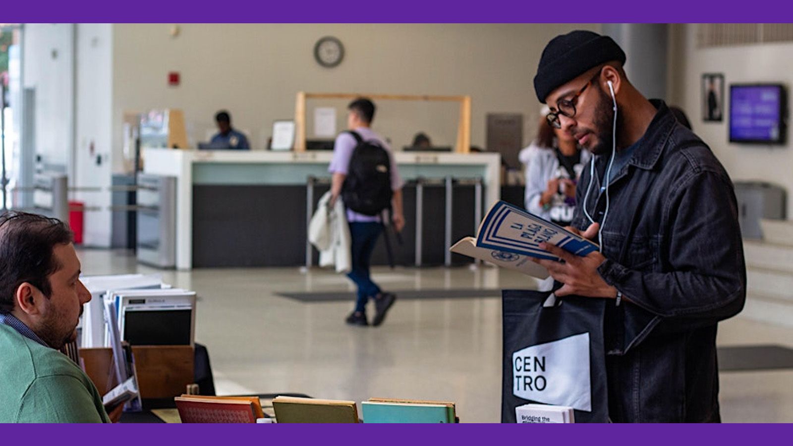 A man in the lobby of Silberman School of Social Work looking at a CENTRO brochure.