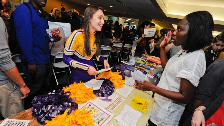 cheerleader at booth engaging with other students