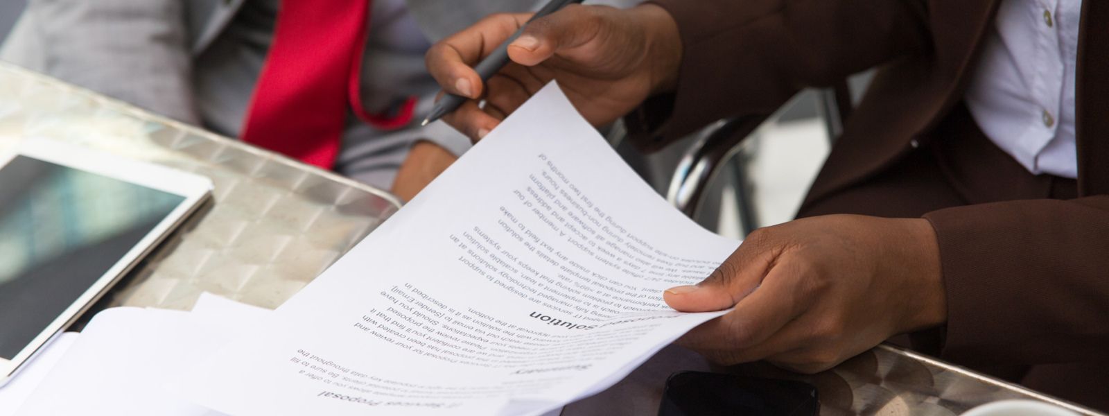 Photo of a pair of hands holding printed documents and a pen