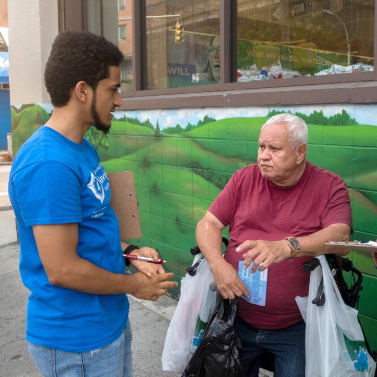 man with clipboard talking to man in wheelchair
