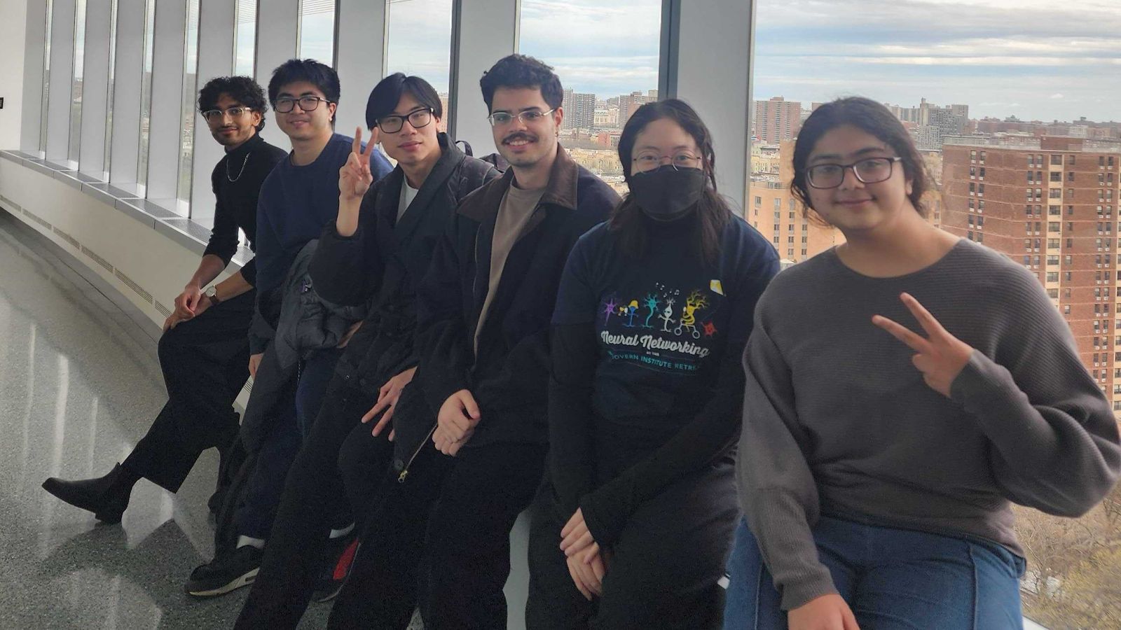 Students sitting in front of a window, posing for a photo.