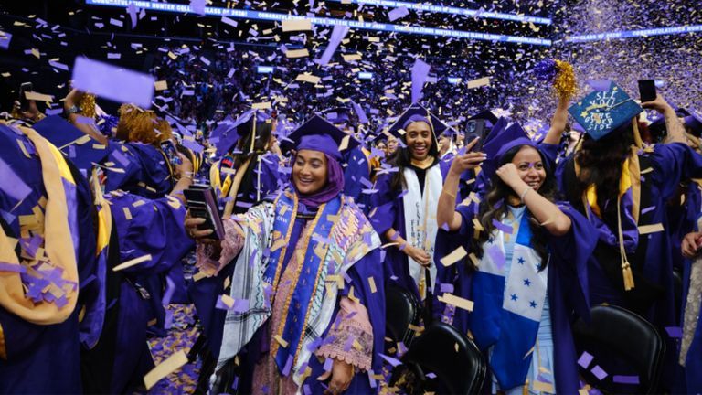 Hunter graduates celebrating graduation while confetti is falling.