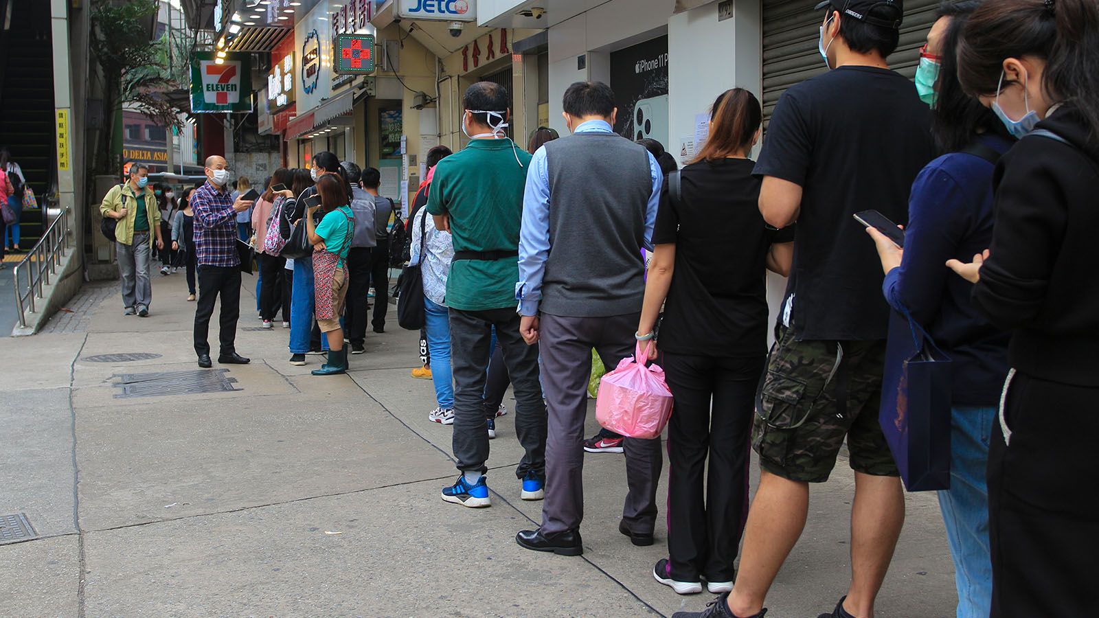 People in face masks waiting on line to be tested for COVID-19.