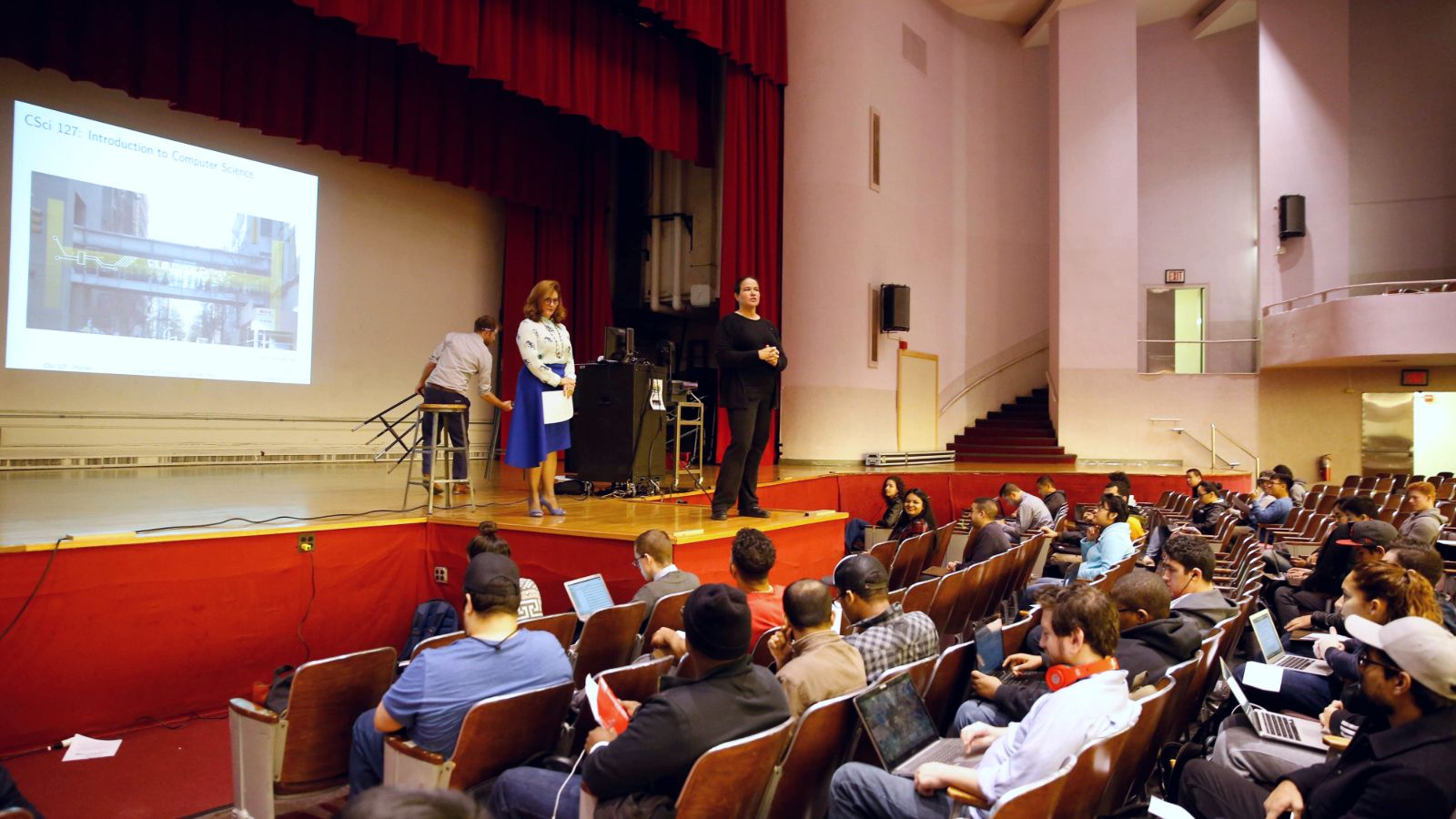 CS127 lecture in auditorium full of students.