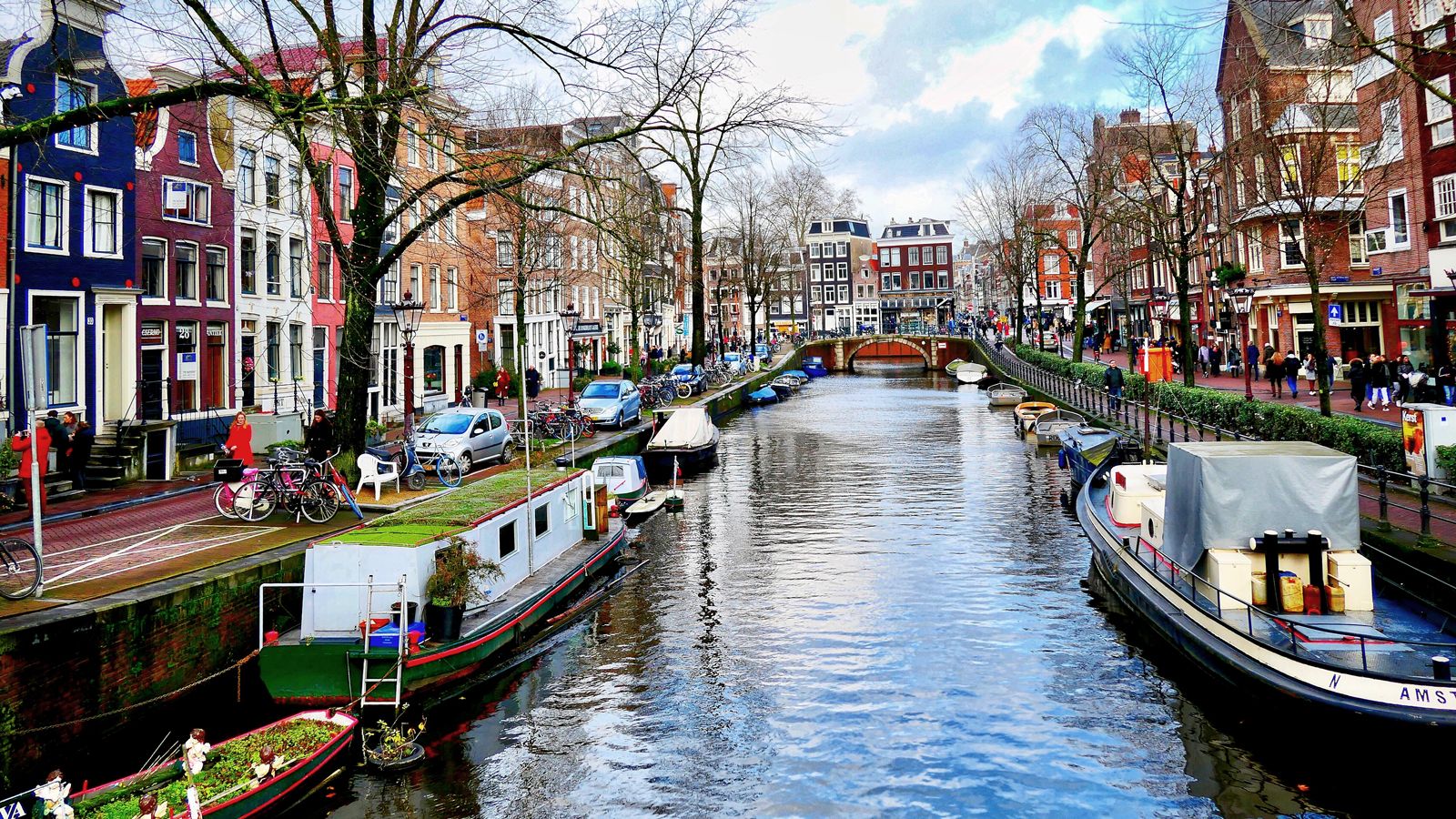 Photo: Boats line the edge of a canal alongside walkways in Amsterdam, Netherlands.
