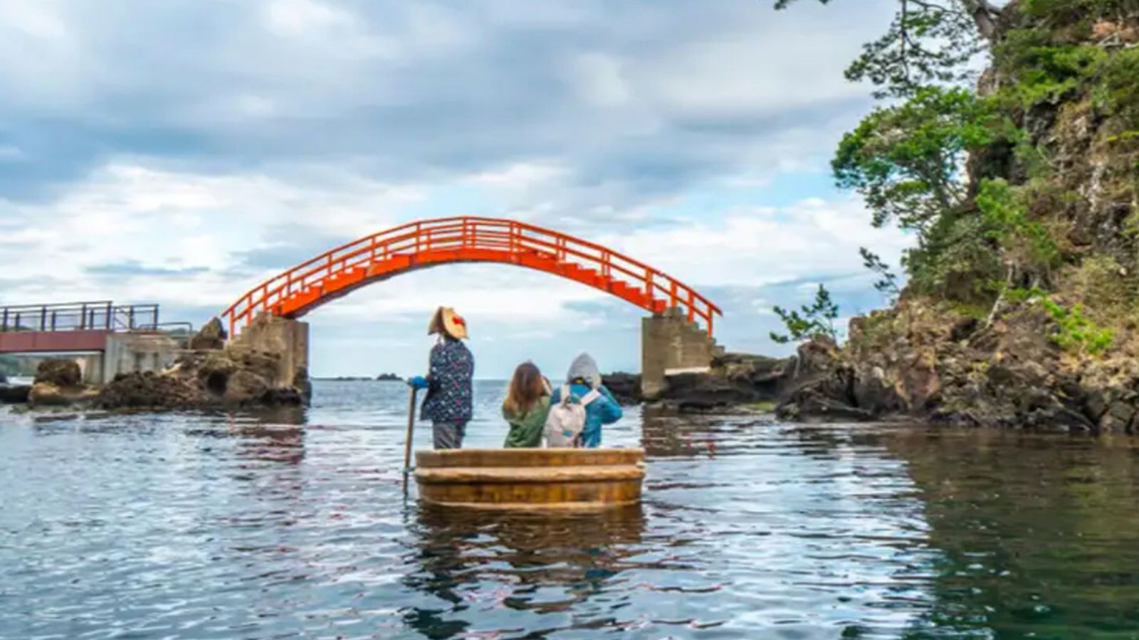 Photo — A small passenger boat approaches a foot bridge on Sado Island, Japan.