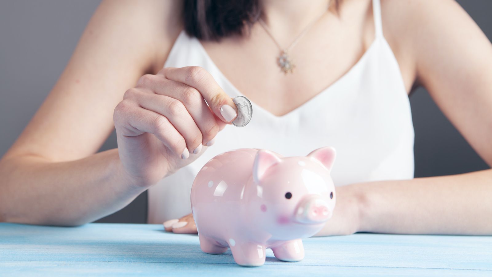 Photo: Student puts a quarter in a piggy bank.