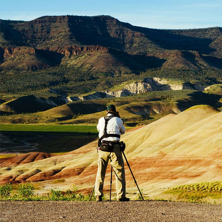 photographer in field with mountain range in background