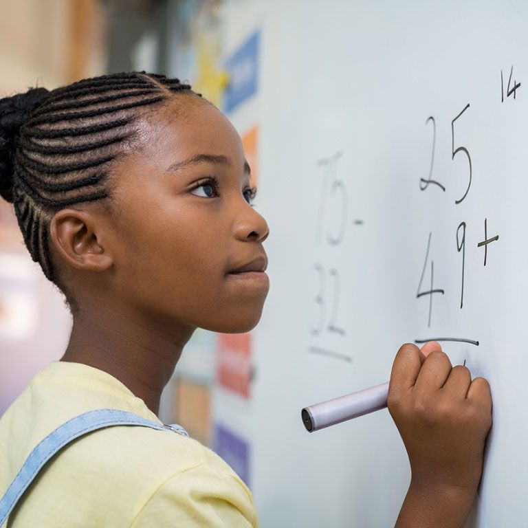 girl doing math problem on whiteboard