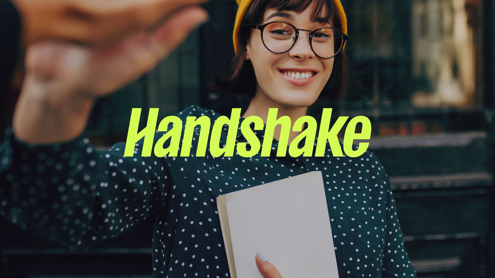 Handshake logo and photo of a young woman with a notebook shaking hands with a person off-camera