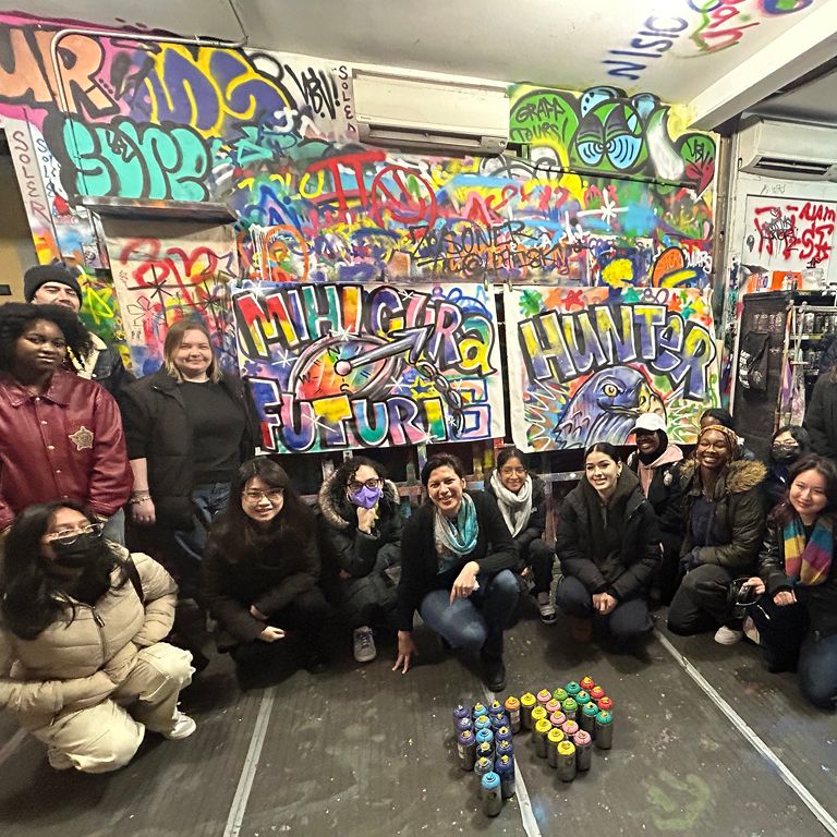Students pose in front of street art they made
