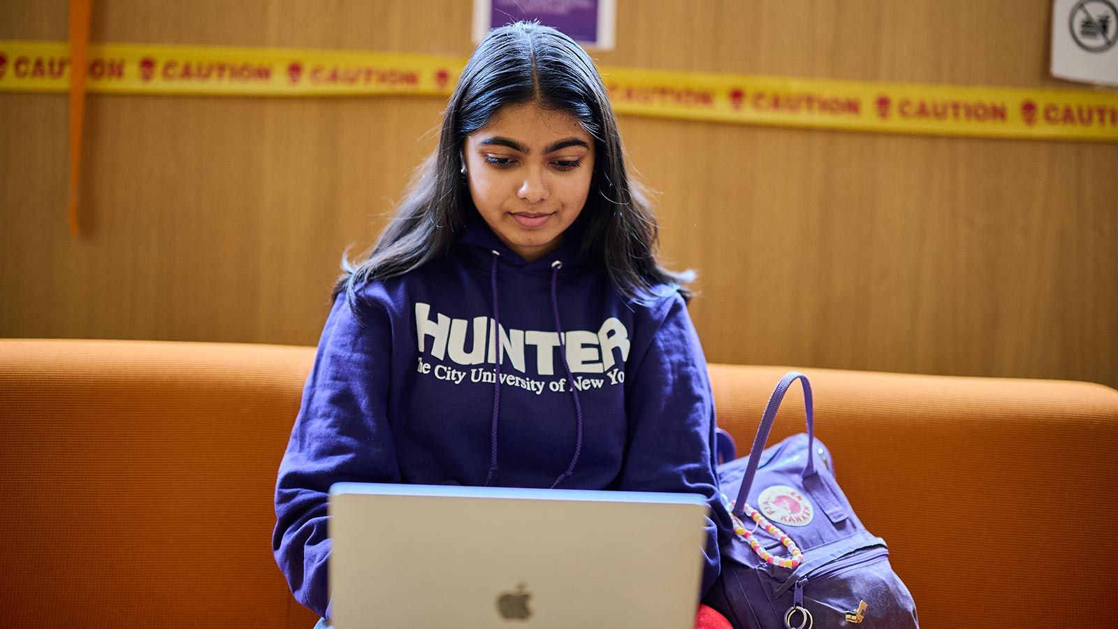student wearing purple Hunter hoodie sitting with laptop