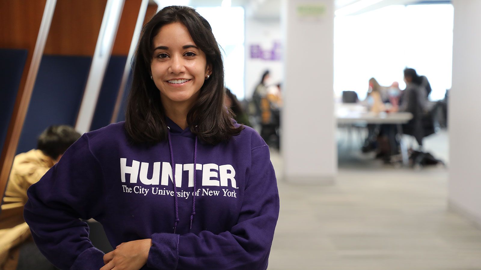 hunter student wearing purple Hunter hoodie in the library