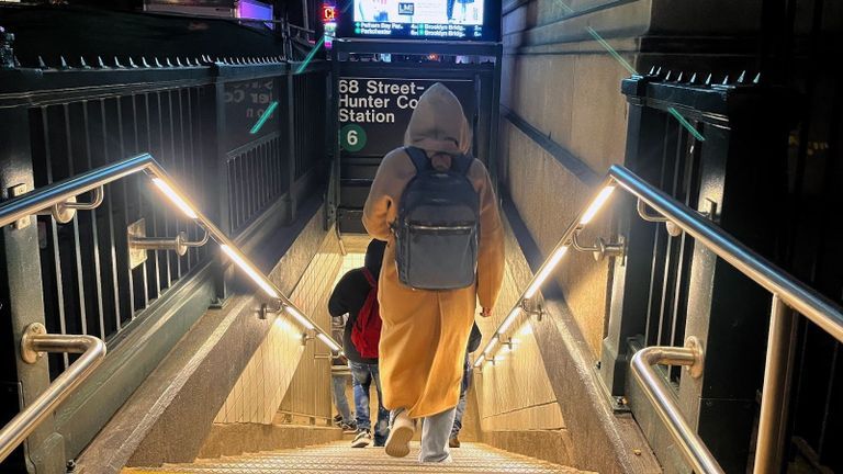 A person walking down the 68th street Hunter College subway entrance