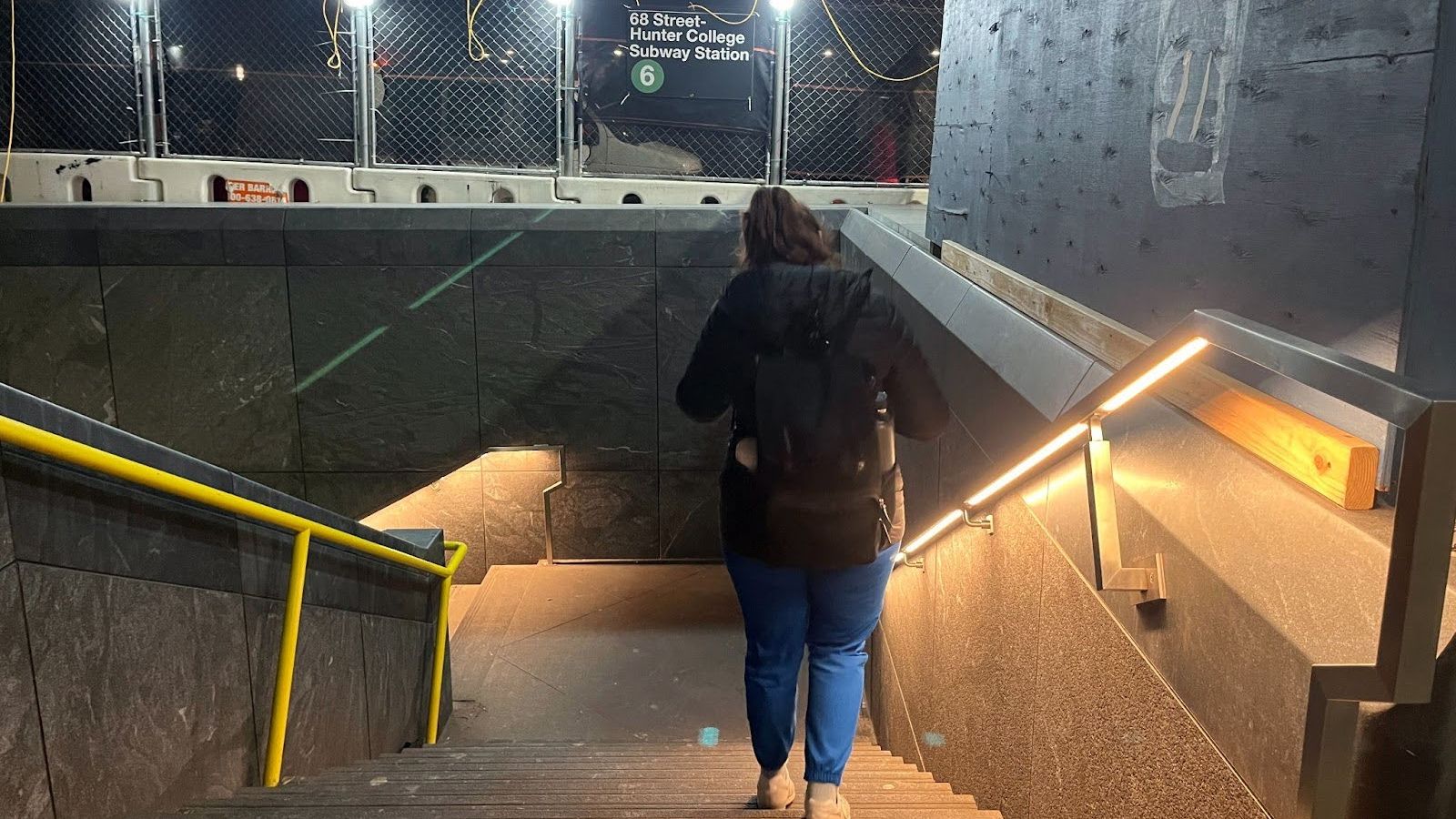 A person walking down the 68th street Hunter College subway entrance.