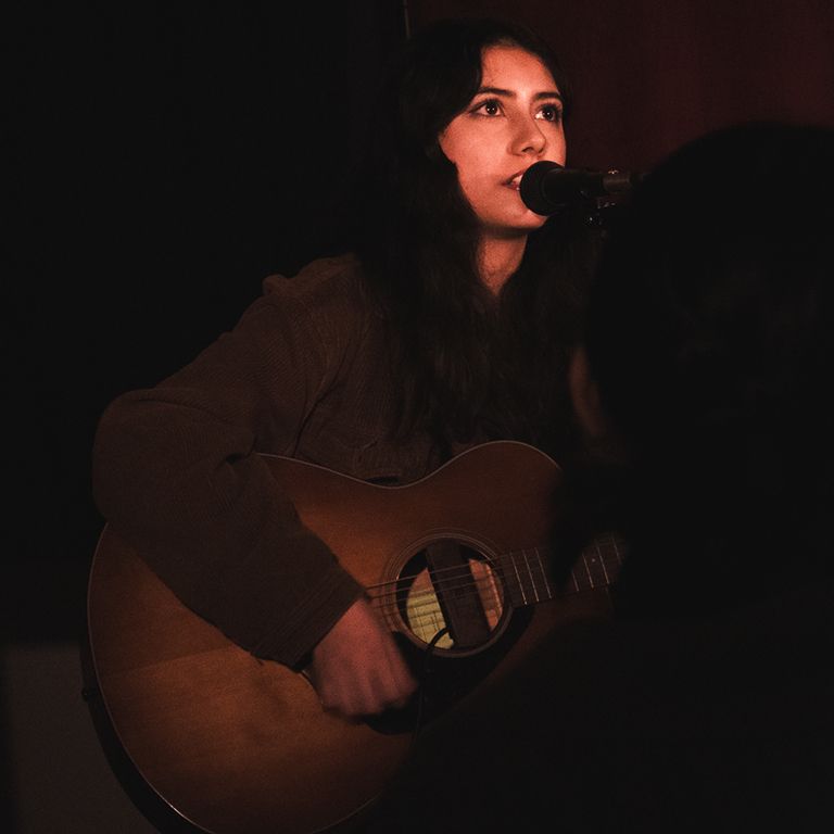 Student sings on stage with a guitar