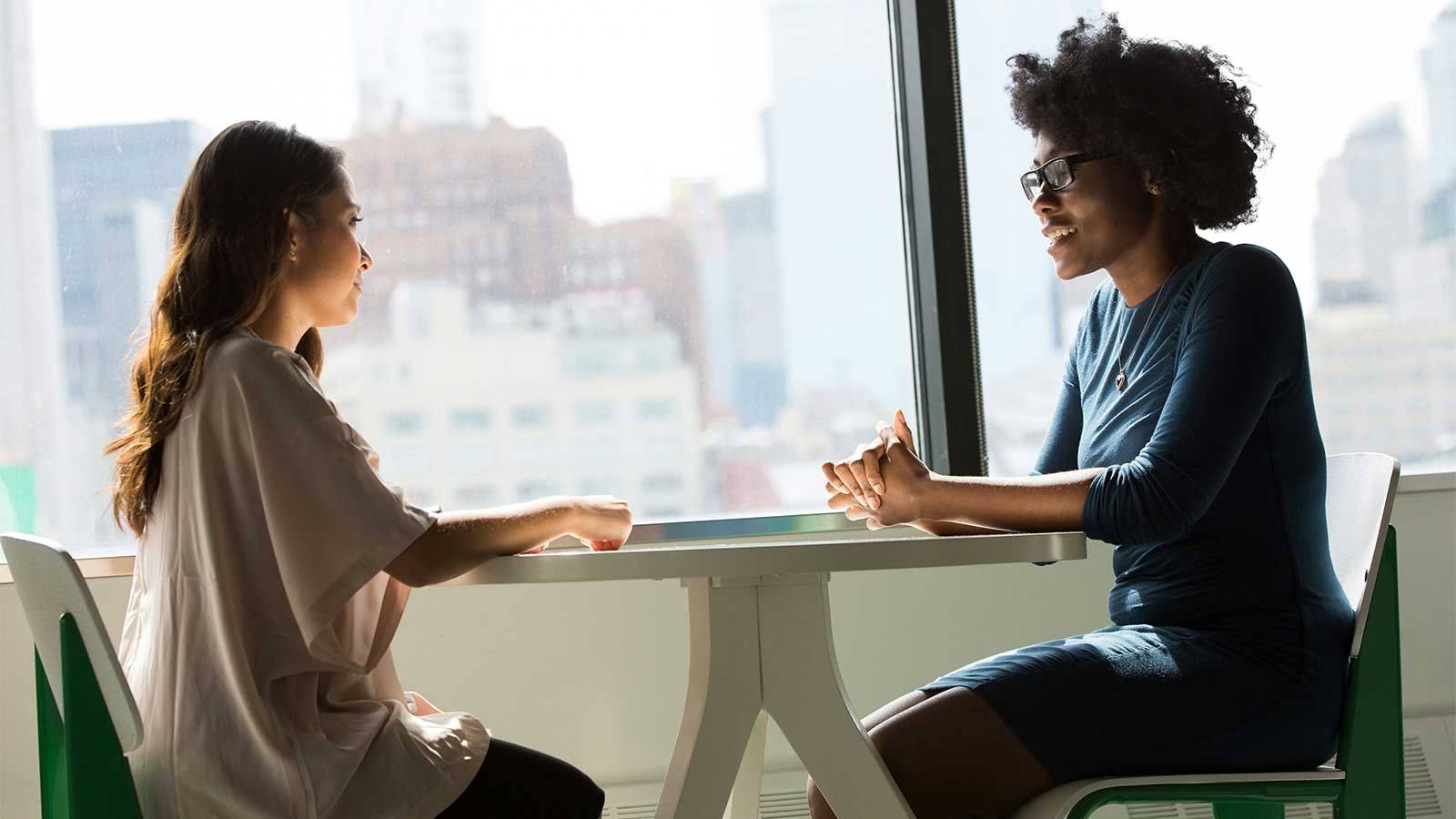 two women sitting across from one another interviewing
