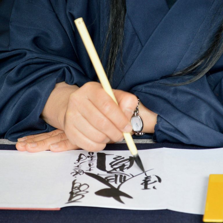 Person writing in Japanese calligraphy.