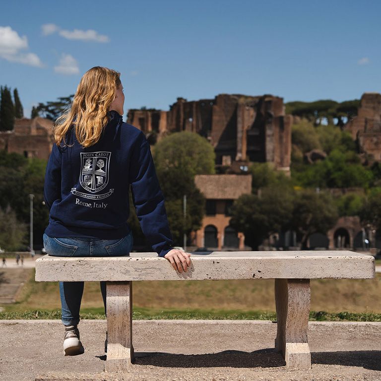 Student sitting on a bench outside John Cabot University campus in Rome, Italy. Photo credit: John Cabot University.