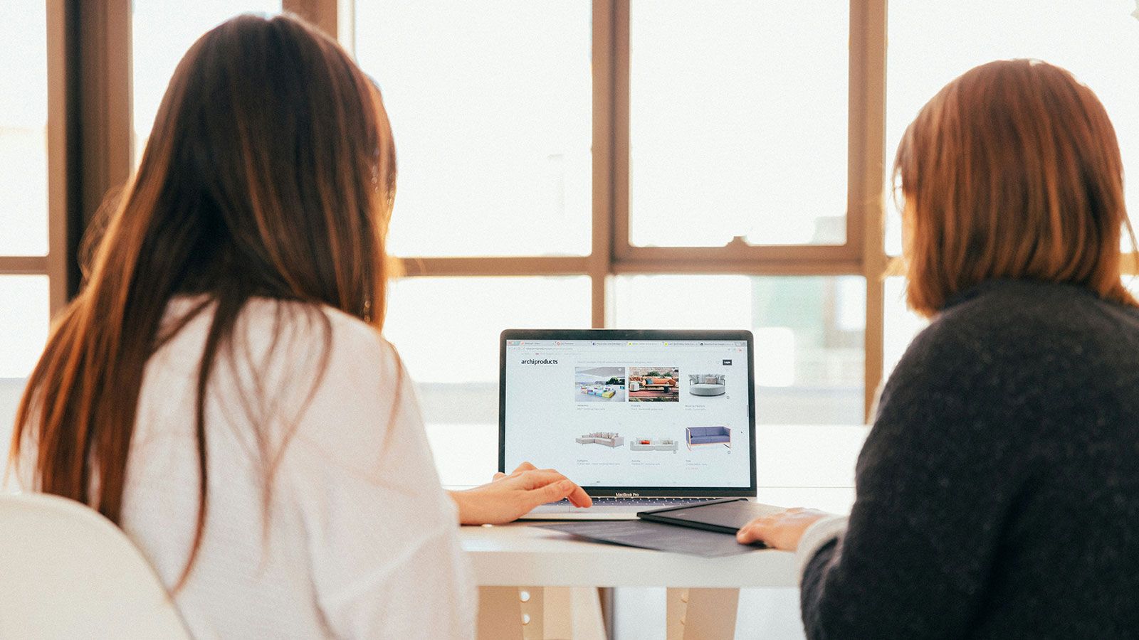 two women at a desk using a laptop