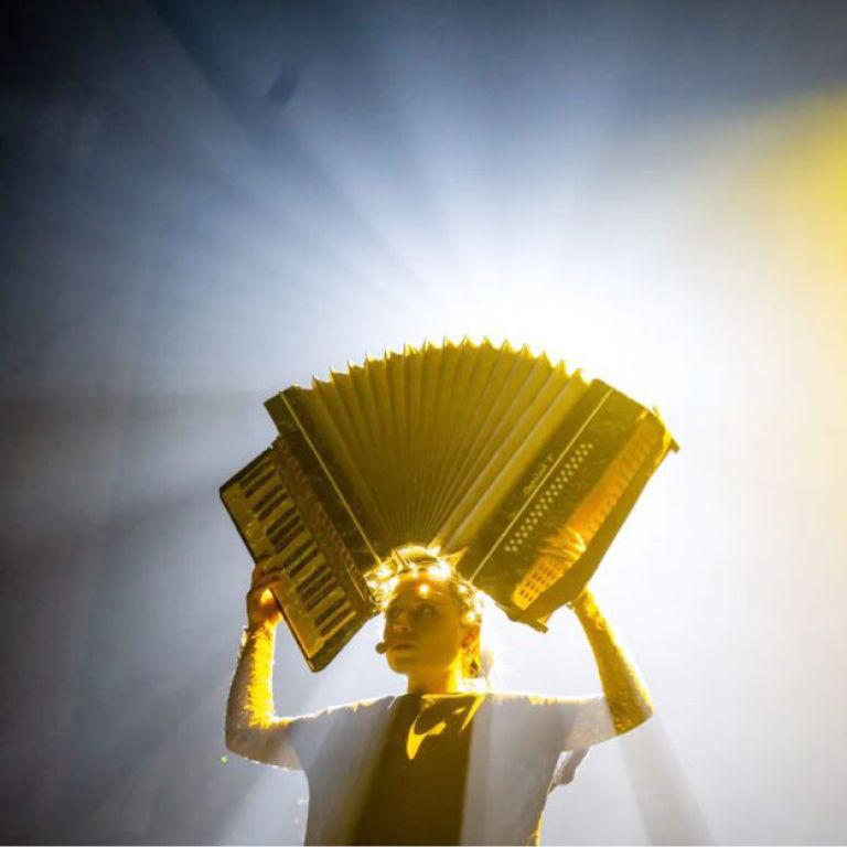 Actress holds accordion over her head on stage.