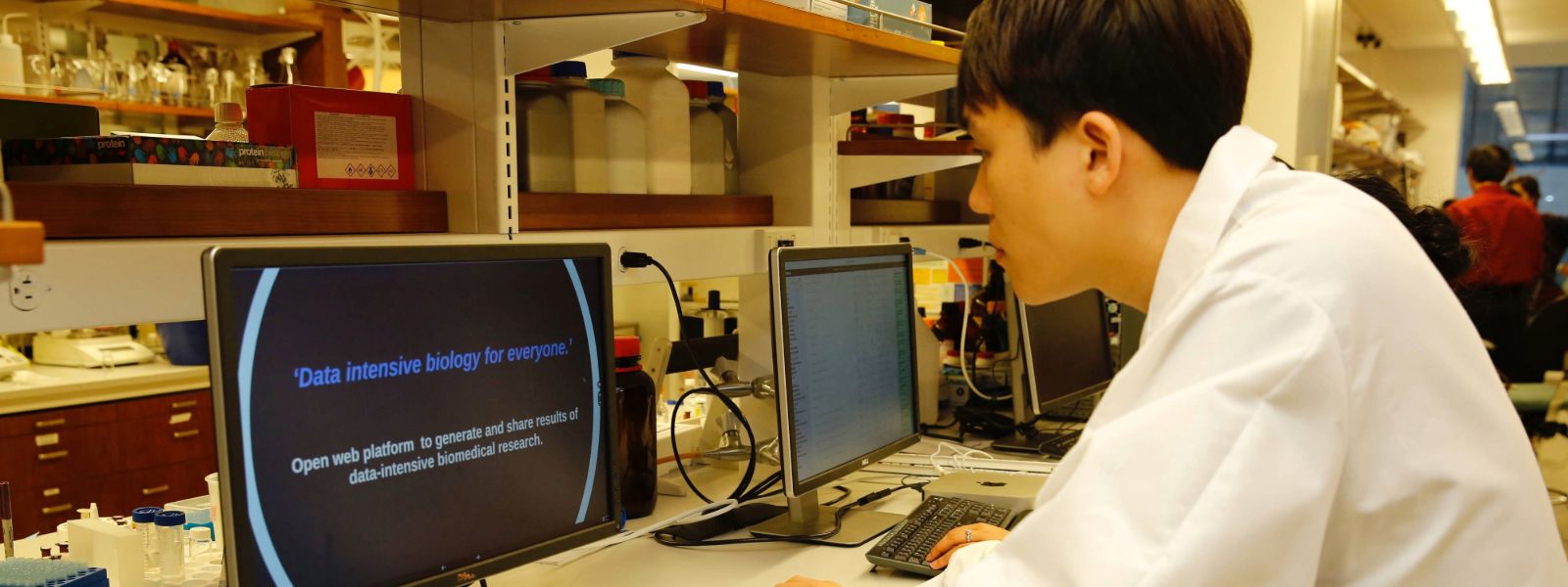 Student wearing lab gown using a computer.