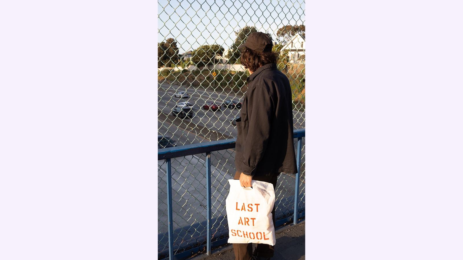 Image of a person looking out at traffic from an overpass.