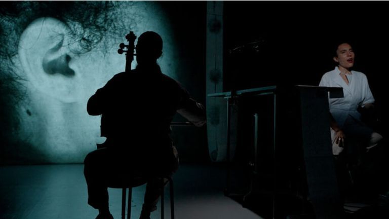 Silhouette of a musician with image projected behind them on stage.
