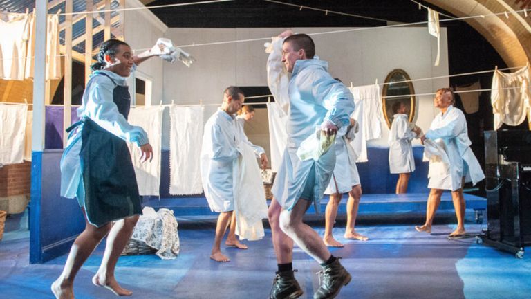 Actors dancing on stage in matching long dress shirts