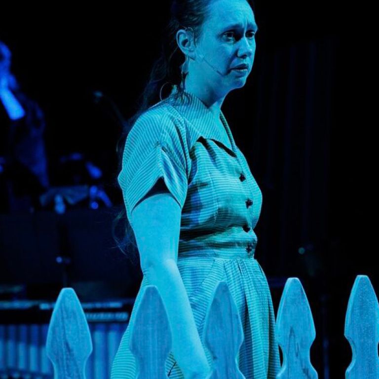 Actress on stage under blue light.