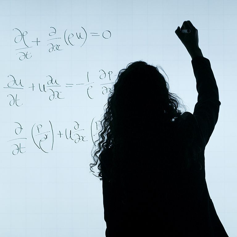 Woman solving equation on white board.