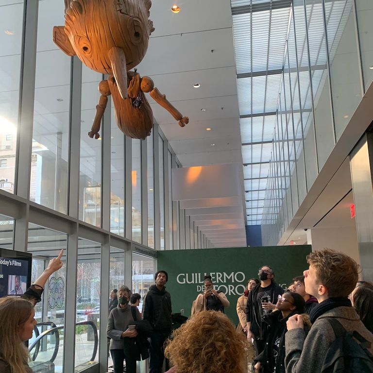 Students looking at Pinocchio sculpture at the Guillermo Del Toro exhibit at MoMA