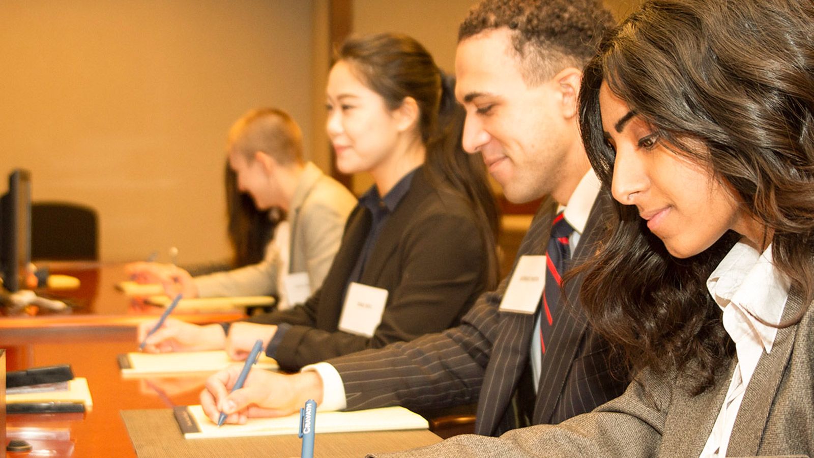 a line of seated students taking notes during a mock trial