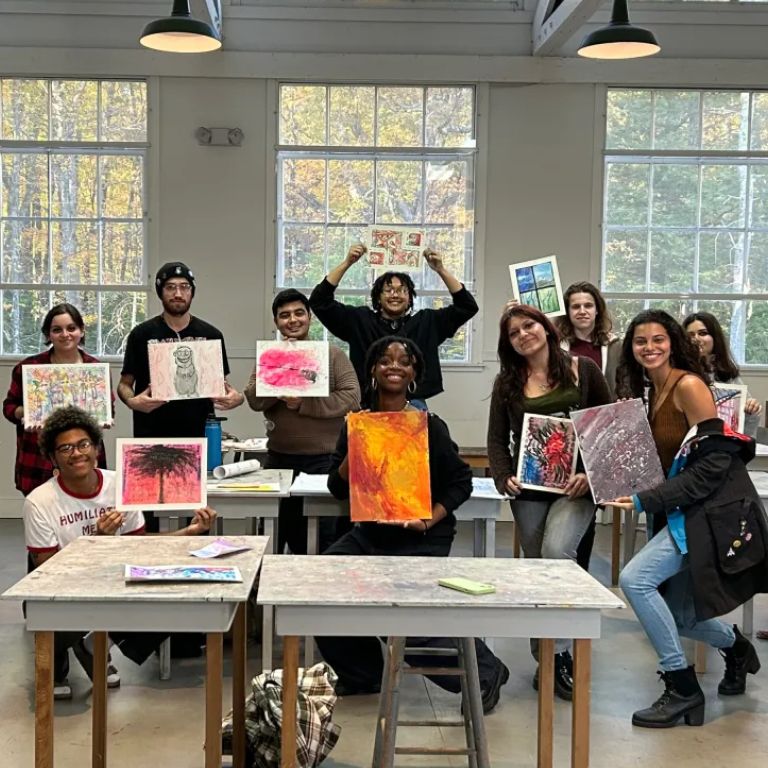 Muse scholars hold up their painting and smile for a photo.