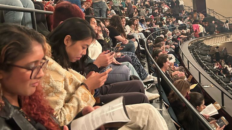 Students reading the program while waiting for a show to start.