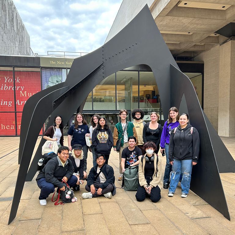 Student pose in front of sculpture at NYPL for the performing arts