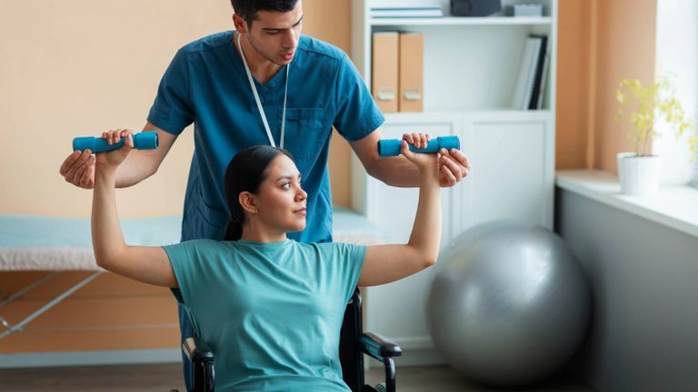 Occupational therapist assisting patient with lifting light dumbbells