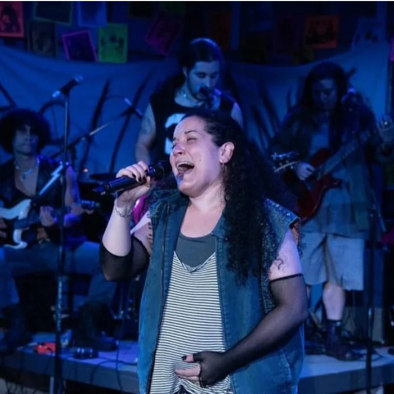Performer sings on stage at ¡Oye! Group.
