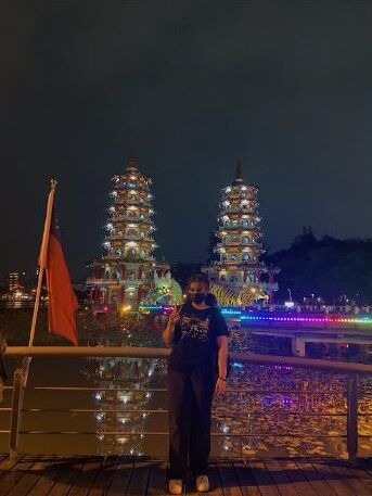 bedoya standing in front of a river with traditional tower buildings lit up in the background