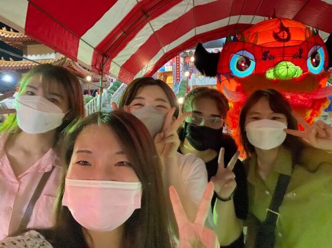 students posing happily under awning wearing covid masks