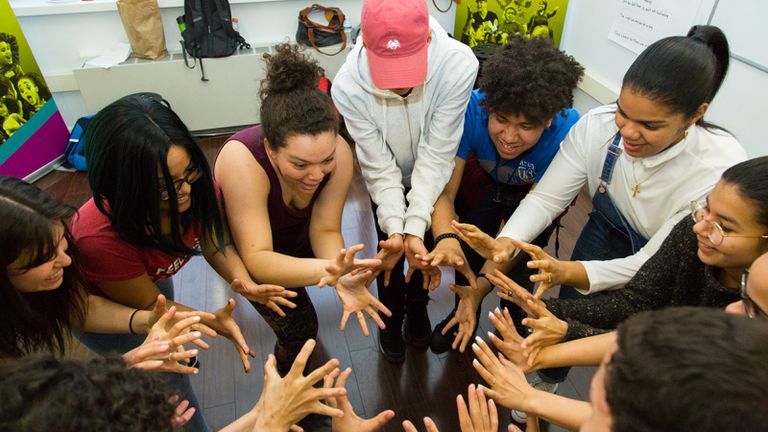 Students and internships put their hands together in a circle.